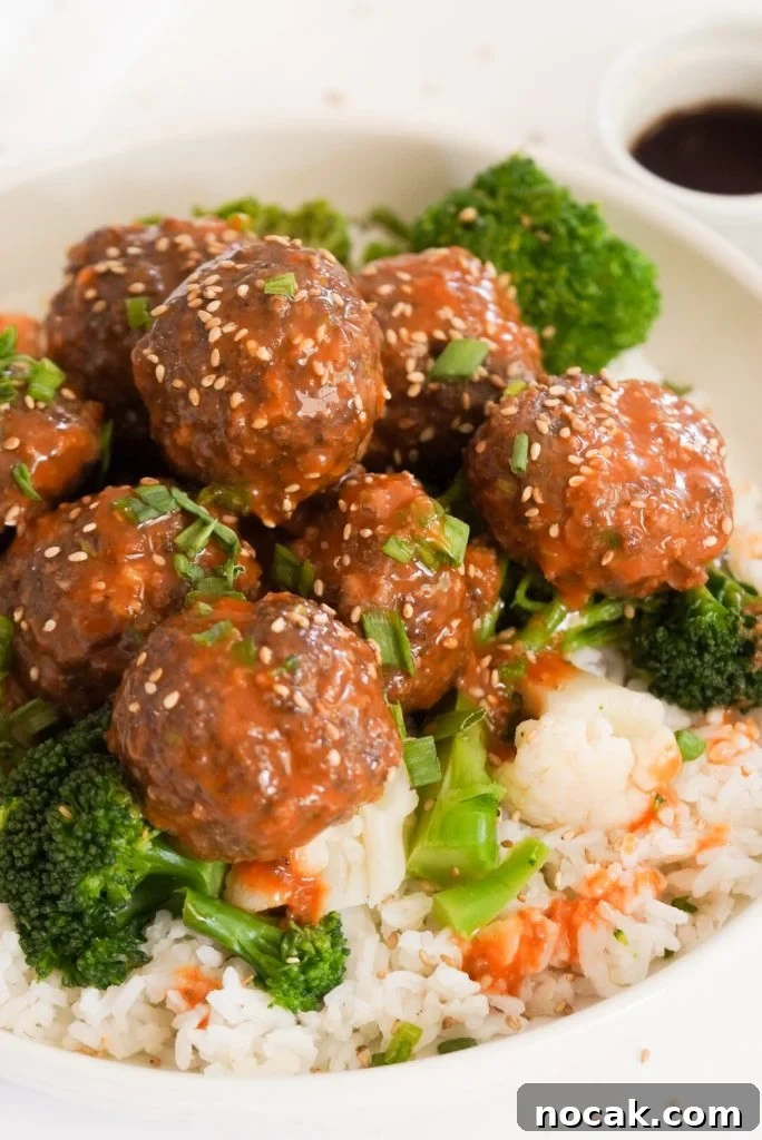 Spicy Firecracker Meatballs with Sweet Chili Glaze 12 45 degree angle shot of a bowl of meatballs over rice with homemade firecracker sauce.