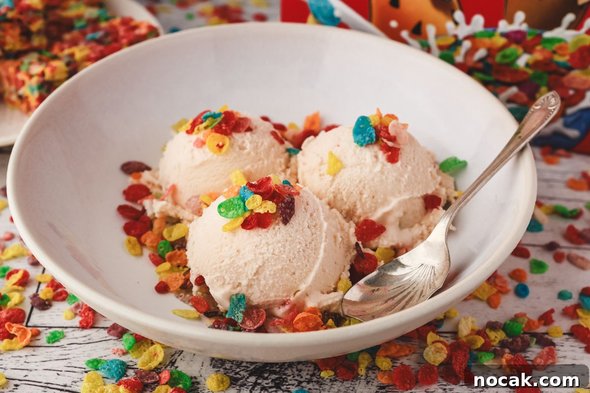 Fruity Pebbles Ice Cream Recipe: Nostalgic Cereal Ice Cream Treat 2 Three scoops of Fruity Pebbles ice cream decorated with Fruity Pebbles cereal, in a bowl with a spoon on the side.