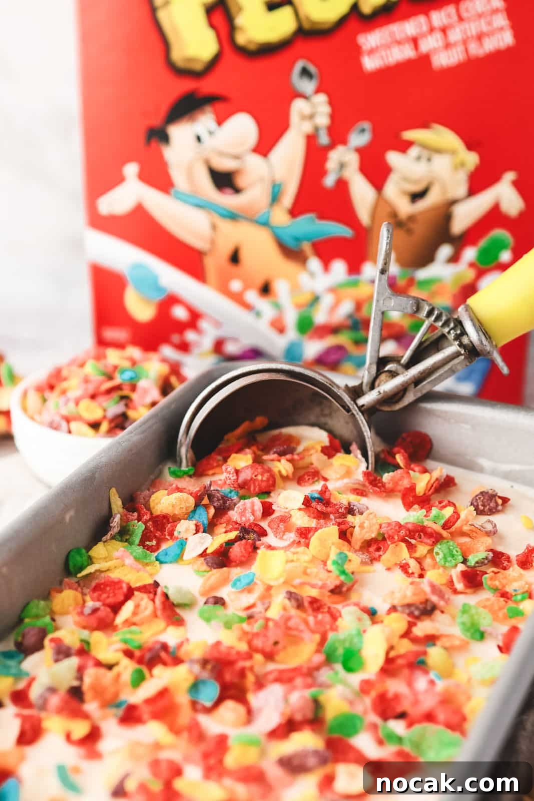 Fruity Pebbles Ice Cream Recipe: Nostalgic Cereal Ice Cream Treat 9 Scooping Fruity Pebbles ice cream from a pan, with box of Fruity Pebbles in the background and text overlay.