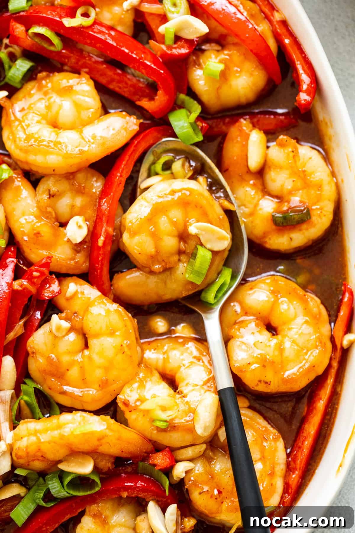 Kung pao shrimp is made with a sweet and spicy sauce, juicy shrimp, and bell peppers for a colorful, high-protein meal ready in 30 minutes. kung pao shrimp in serving dish.