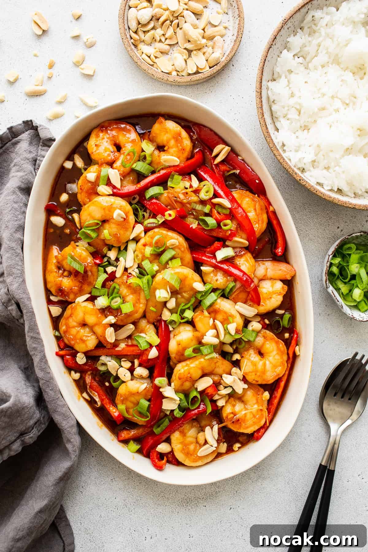 Kung pao shrimp is a 30-minute stir fry recipe that's sweet and spicy. We're serving ours with white rice and bell peppers. kung pao shrimp in serving platter.