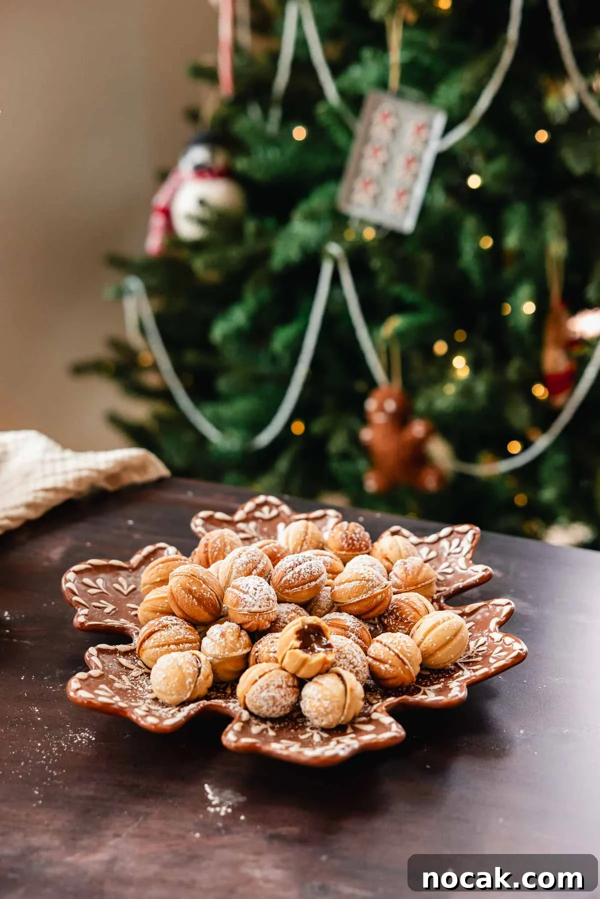Oreshki Walnut Cookies Recipe — Russian Fillable Pastry Treats 3 walnut cookies on a plate with Christmas tree in the back