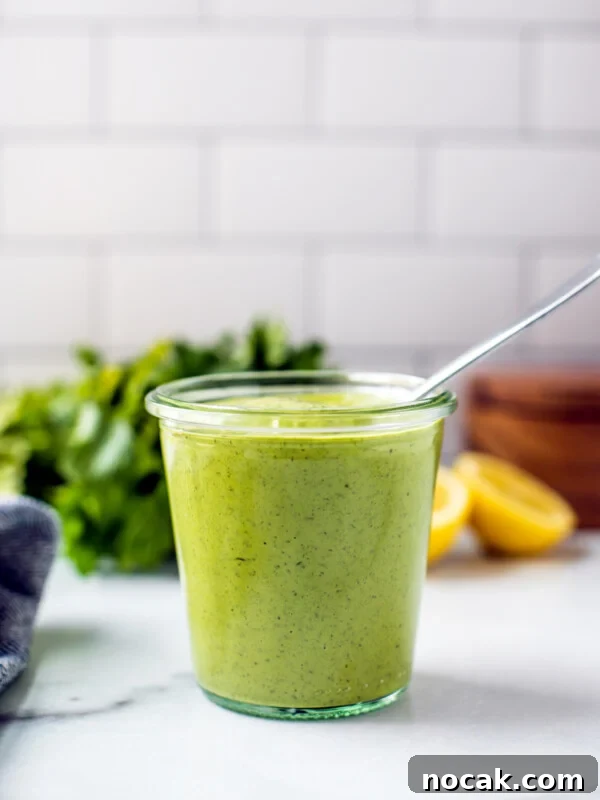 Homemade Ketchup Recipe: Simple from-Scratch Tomato Sauce 9 A jar of bright green dressing with lemons and parsley in the background in front of a white-tiled wall.