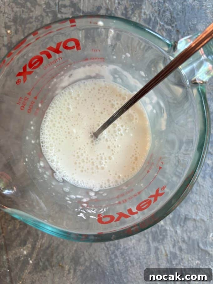 Malabi Rose Water Milk Pudding with Vegan Options 5 overhead image of a pyrex liquid measuring cup with the ingredients for Malabi being mixed together with a spoon