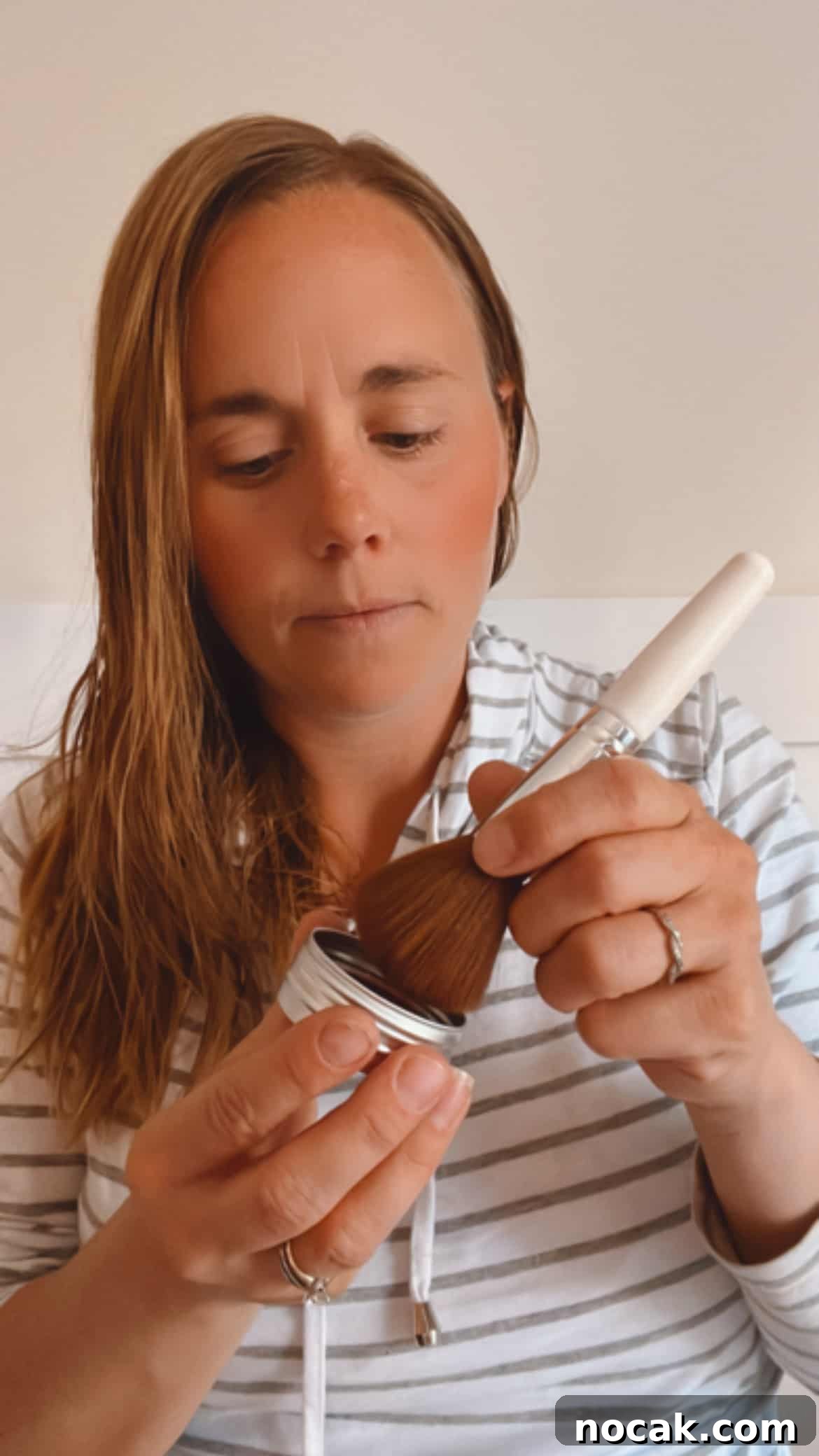 DIY Natural Makeup Recipes: Homemade Cosmetics for Glowing Skin 2 Applying homemade blush with a small applicator.