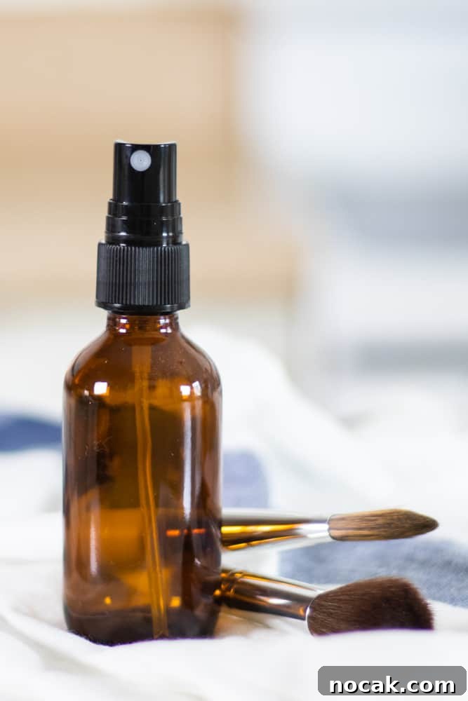 DIY Natural Makeup Recipes: Homemade Cosmetics for Glowing Skin 7 glass spray bottle on white and blue towel with makeup brushes in background