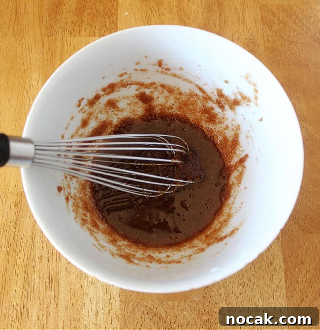 Fudgy Dark Chocolate Cookies — Nut Free Recipe 5 Whisking sugar and oil in a white bowl.
