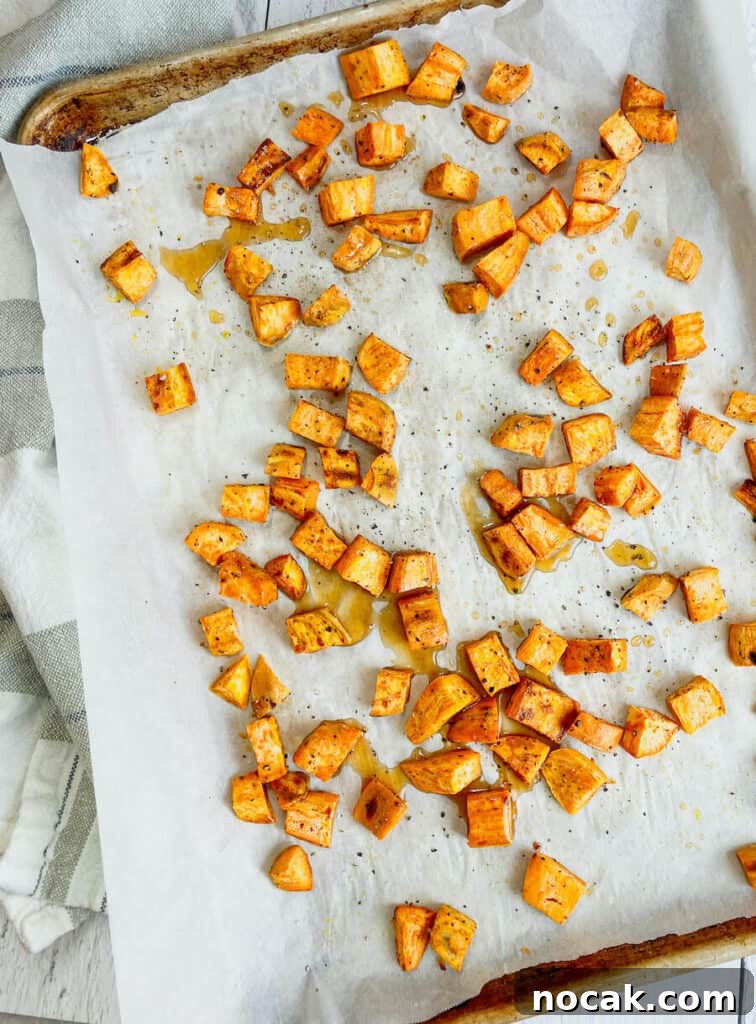Maple-Glazed Roasted Sweet Potatoes with Crispy Edges 3 Cooked sweet potatoes on a parchment paper lined sheet pan.
