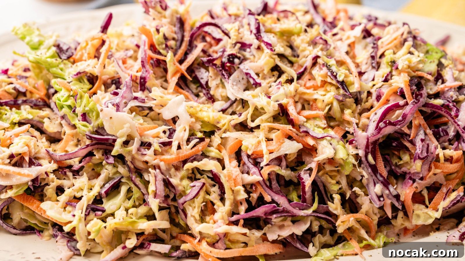 23 Crowd-Pleasing Cookout Recipes for Memorial Day Weekend 15 A close-up of coleslaw made with shredded green and purple cabbage, carrots, and creamy dressing on a white plate.