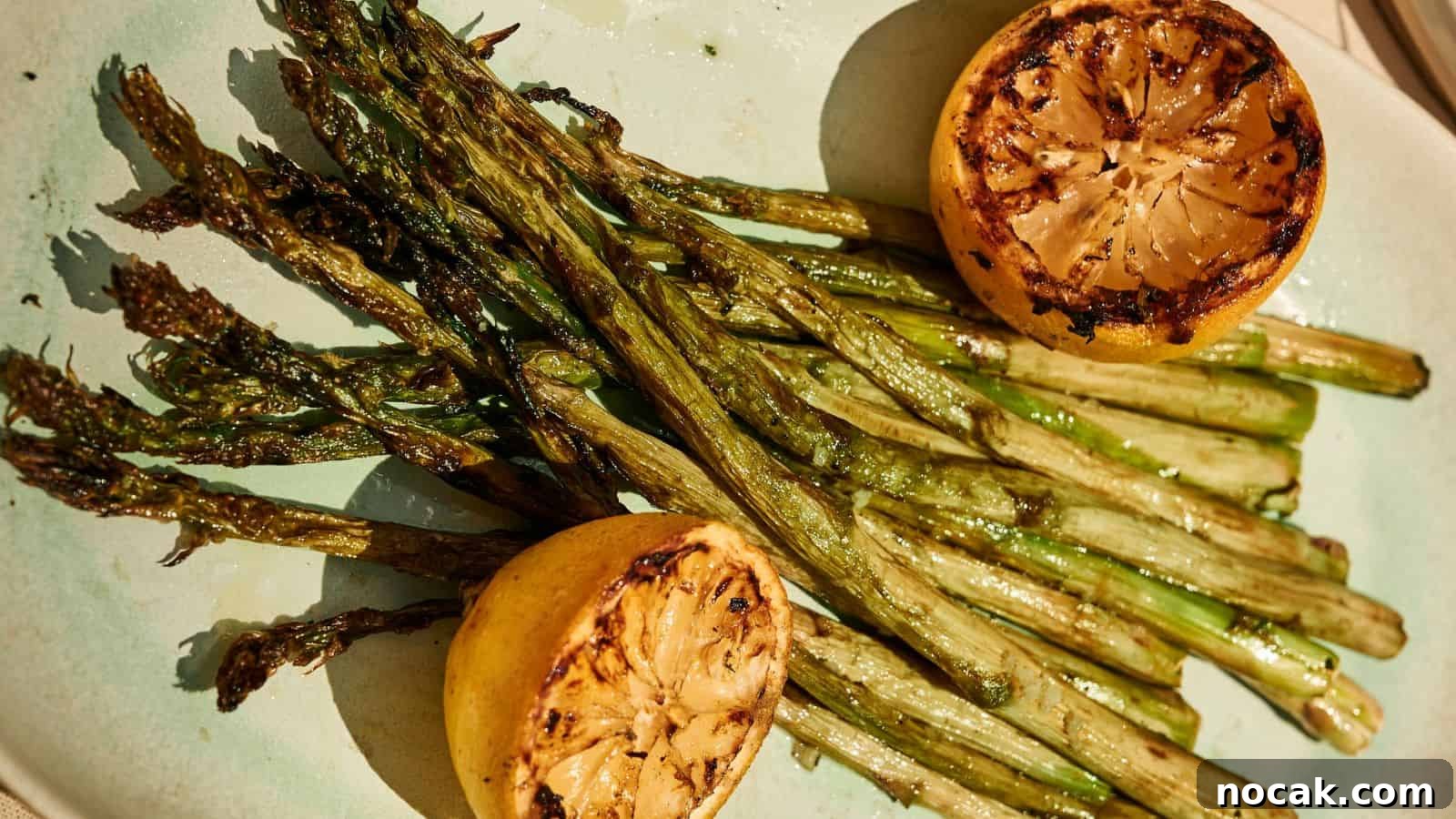 23 Crowd-Pleasing Cookout Recipes for Memorial Day Weekend 18 Grilled asparagus spears served on a plate with two charred lemon halves.