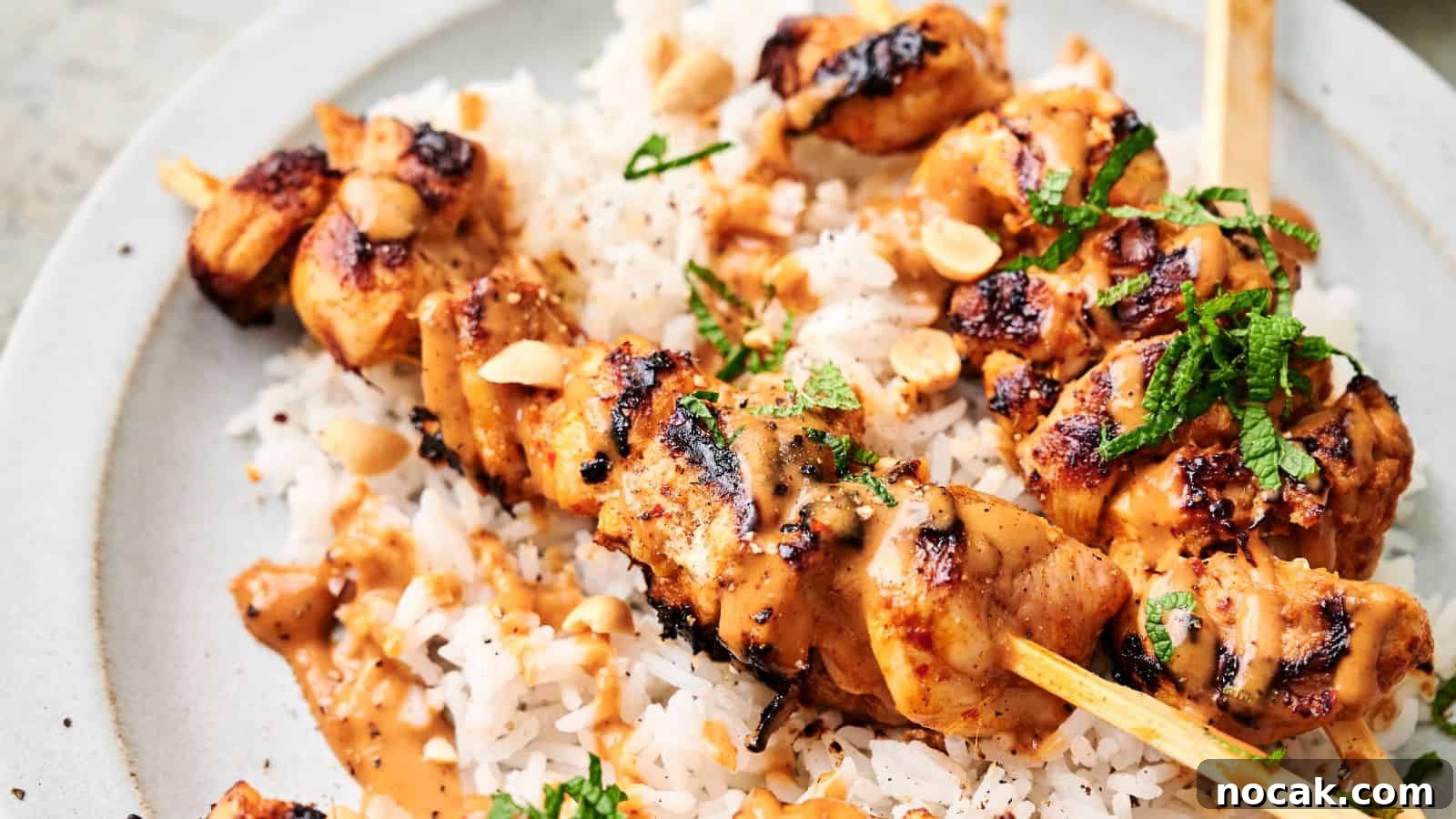 23 Crowd-Pleasing Cookout Recipes for Memorial Day Weekend 7 Thai chicken skewers topped with a creamy sauce and garnished with chopped herbs and peanuts, served over a bed of white rice.