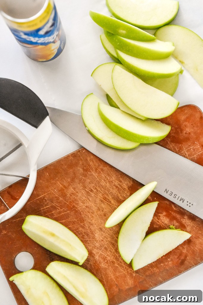 Air Fryer Apple Pie Crescent Rolls Recipe 5 cutting up apples on a cutting board to make air fryer apple pie crescent rolls.