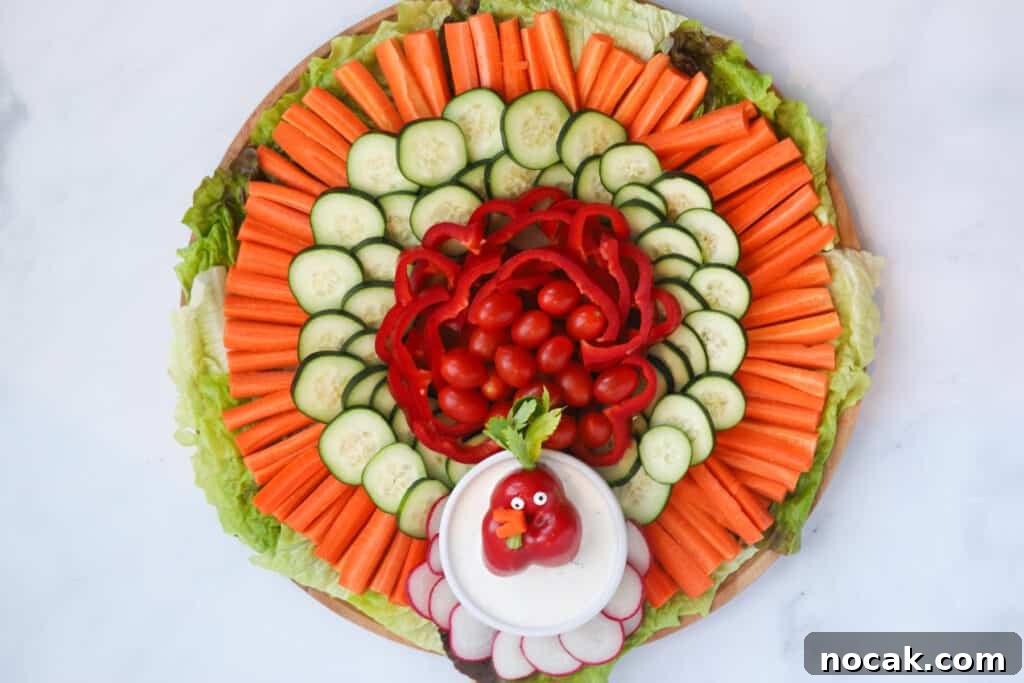 Festive Holiday Vegetable Tray Ideas for Entertaining 4 A thanksgiving veggie platter made with carrots, cucumbers, bell peppers, radishes and cherry tomatoes with a ramekin of dip decorated with a veggie face.