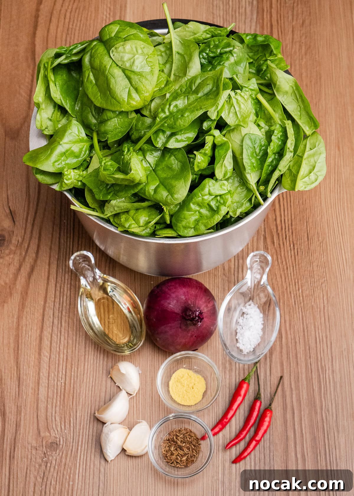 Saag Bhaji Recipe: Creamy Indian Spinach Curry with Spices 13 A bowl of spinach,one red onion, three red chillies, four cloves of garlic, sea salt, vegetable oil, cumin seeds and Asafoetida in glass dishes