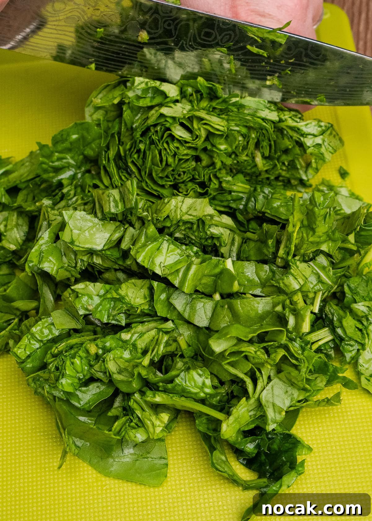 Saag Bhaji Recipe: Creamy Indian Spinach Curry with Spices 19 Chopping up spinach with a knife on a green chopping board
