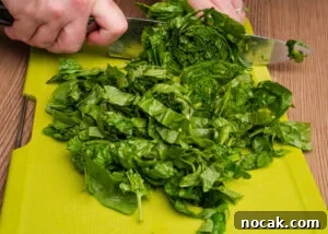 Saag Bhaji Recipe: Creamy Indian Spinach Curry with Spices 4 Slicing spinach with a knife on a chopping board
