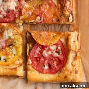 Crispy Puff Pastry Tomato Tart with Herbed Goat Cheese 13 closeup of a sliced puff pastry tomato tart on parchment paper