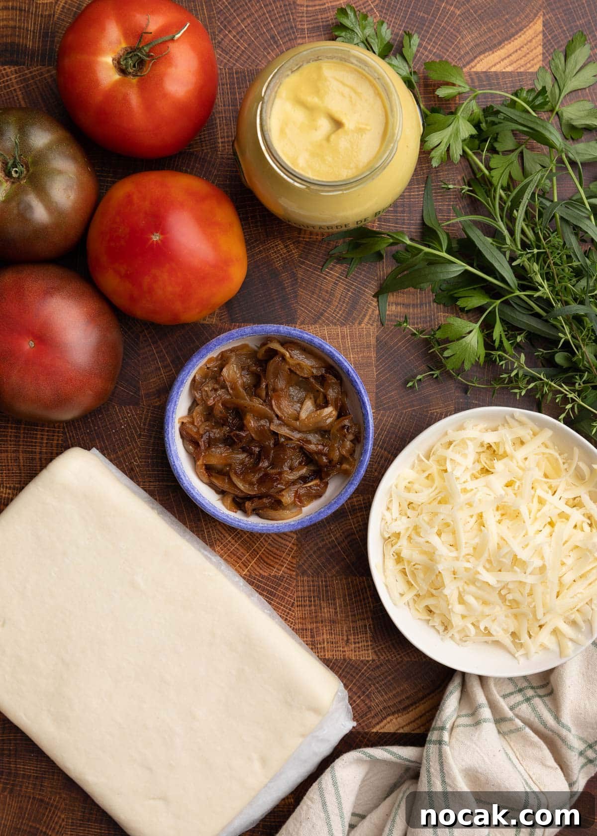 Crispy Puff Pastry Tomato Tart with Herbed Goat Cheese 3 overhead photo of ingredients needed to make a puff pastry tomato tart on a wood cutting board