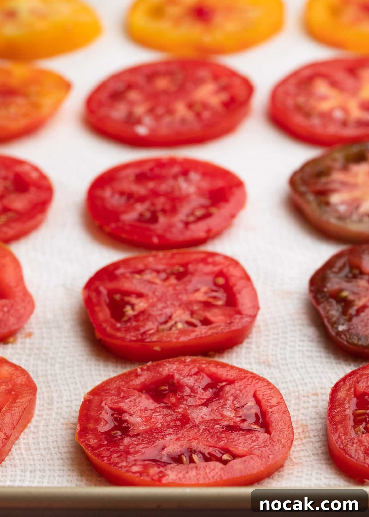 Crispy Puff Pastry Tomato Tart with Herbed Goat Cheese 4 sliced tomatoes on a paper towel-lined baking sheet sprinkled with salt