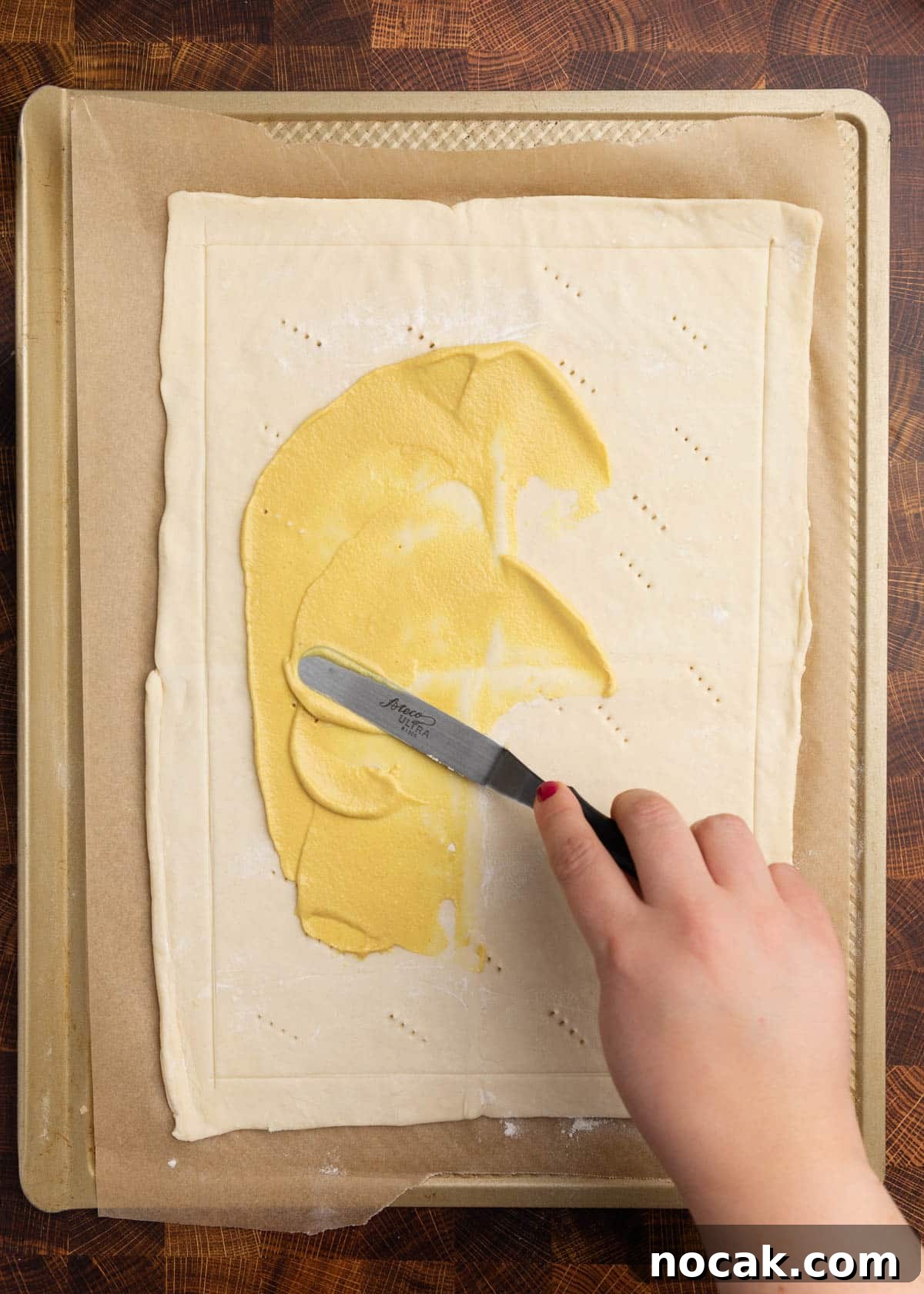 Crispy Puff Pastry Tomato Tart with Herbed Goat Cheese 7 overhead photo of spreading Dijon mustard onto a puff pastry dough on a parchment lined baking sheet