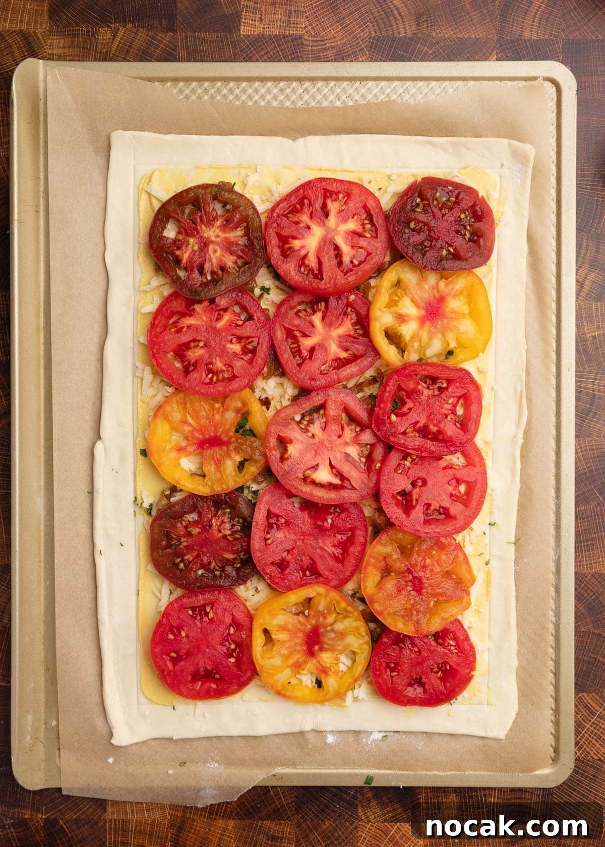 Crispy Puff Pastry Tomato Tart with Herbed Goat Cheese 9 overhead photo of an unbaked puff pastry tomato tart on a parchment lined baking sheet