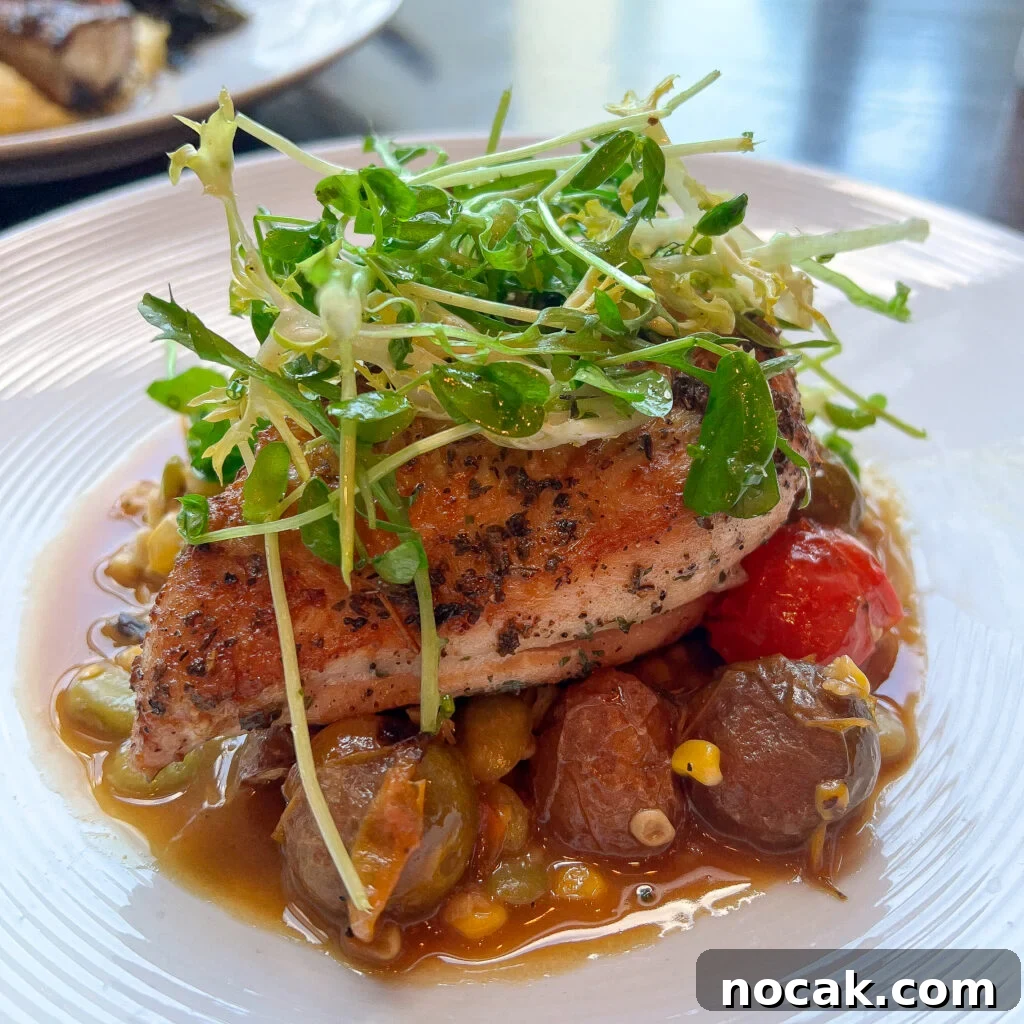 A plated dish featuring grilled fish with vegetables and microgreens.