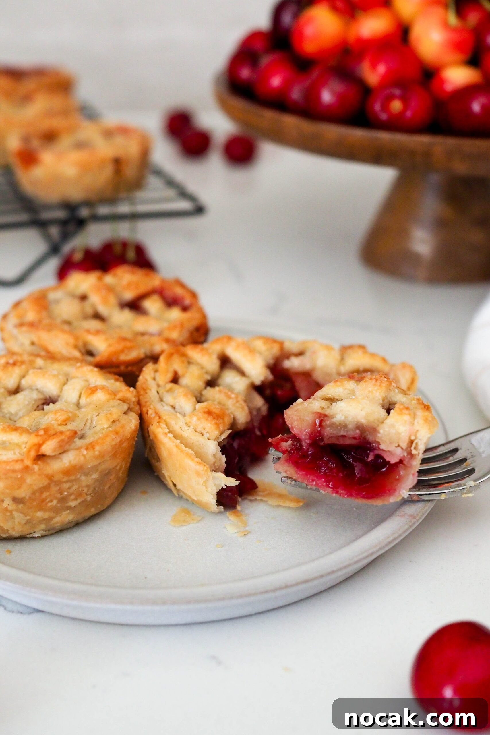 Mini Cherry Pies Recipe: Perfect Bite-Sized Cherry Hand Pies 2 A fork pulls a piece of mini cherry pie off a plate.