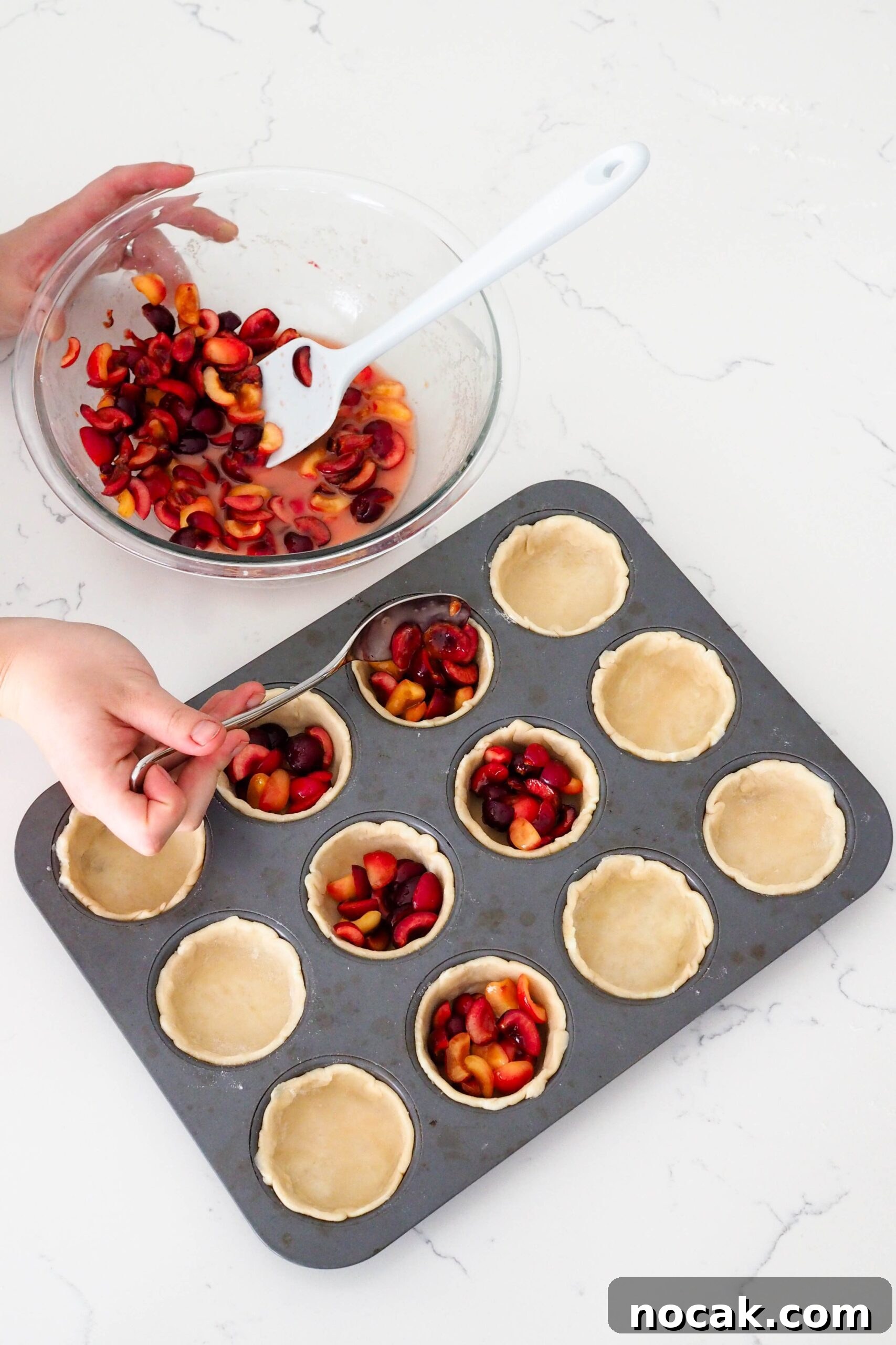 Mini Cherry Pies Recipe: Perfect Bite-Sized Cherry Hand Pies 8 A hand uses a tablespoon to spoon cherries into mini pies.
