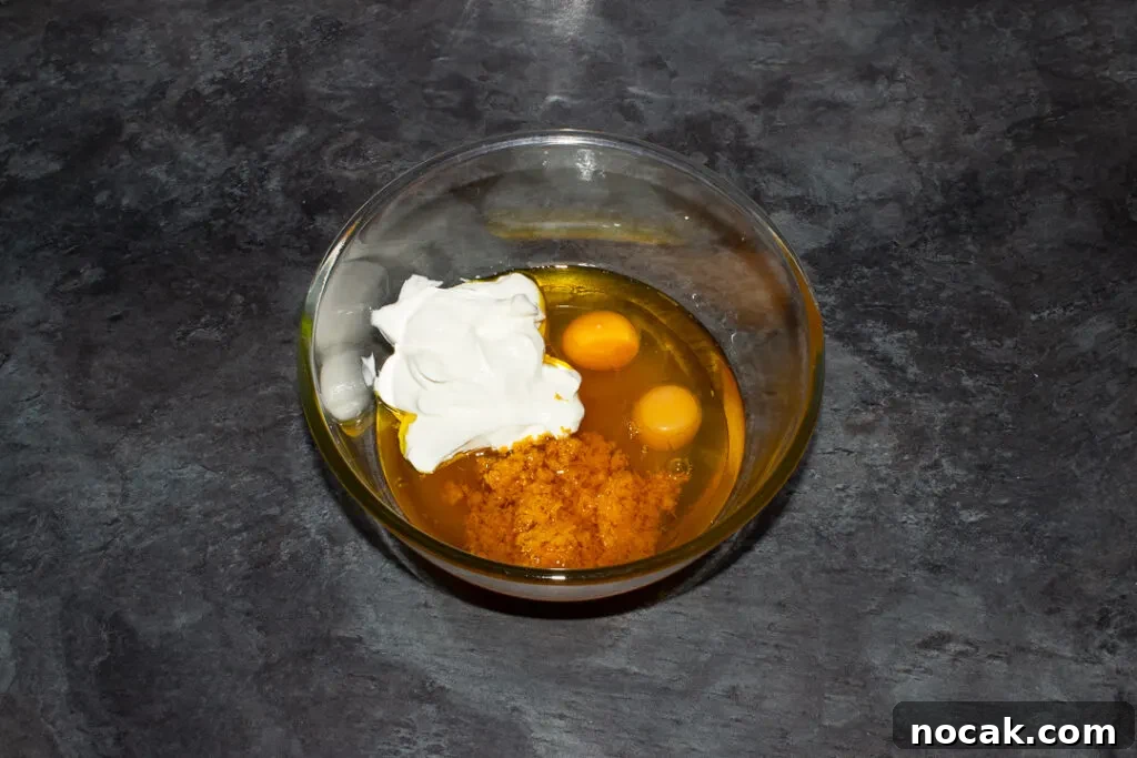 Sticky Orange Glaze Cake Recipe with Zesty Citrus Flavor 13 Sticky orange cake wet batter ingredients in a glass bowl on a kitchen worktop.