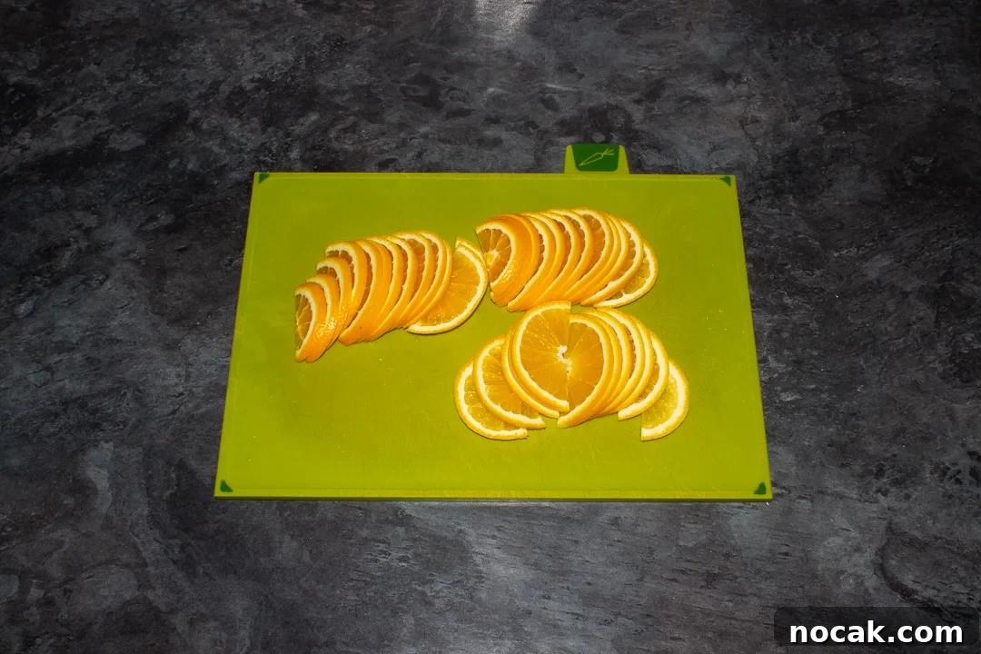 Sticky Orange Glaze Cake Recipe with Zesty Citrus Flavor 23 Thinly sliced semicircle orange slices on a green chopping board on a kitchen worktop.