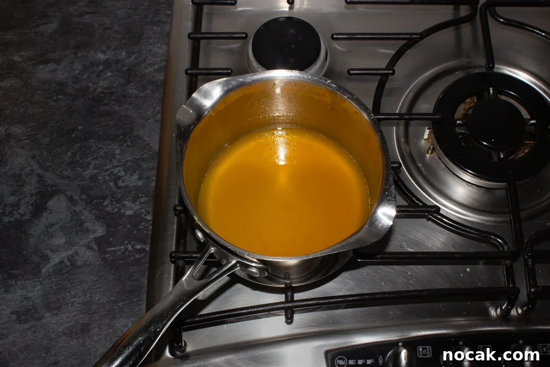 Sticky Orange Glaze Cake Recipe with Zesty Citrus Flavor 25 Orange syrup in a saucepan on the stove top.