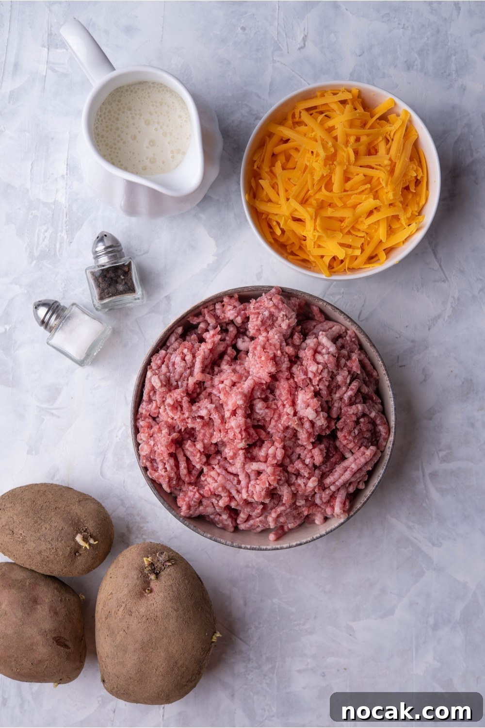 Hearty Hamburger and Potato Casserole with Canned Soup 4 An assortment of ingredients including 3 potatoes and bowls of ground beef, shredded cheese, milk, salt and pepper.