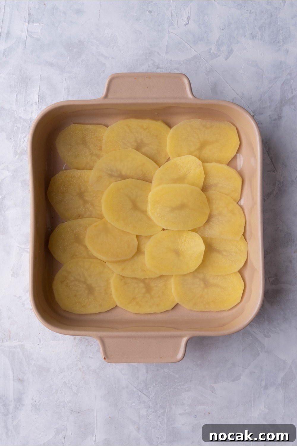 Hearty Hamburger and Potato Casserole with Canned Soup 5 Brown baking sheet with a layer of thinly sliced potatoes.
