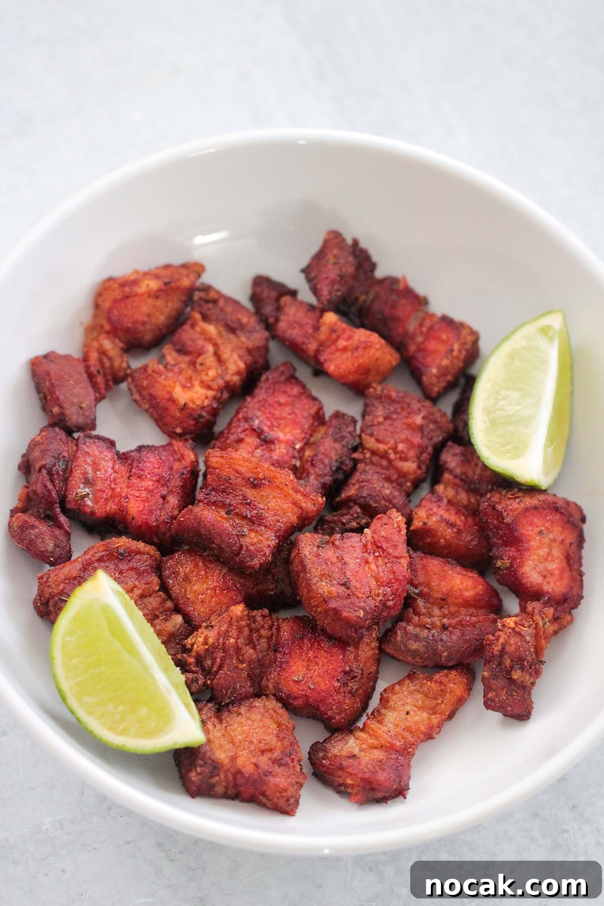 Crispy Air Fryer Pork Belly Recipe: Perfect Crackling in Minutes 2 air fryer pork belly in a white plate with two lime wedges.