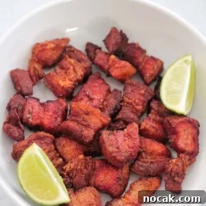 Crispy Air Fryer Pork Belly Recipe: Perfect Crackling in Minutes 7 air fryer pork belly in a white plate with two lime wedges.