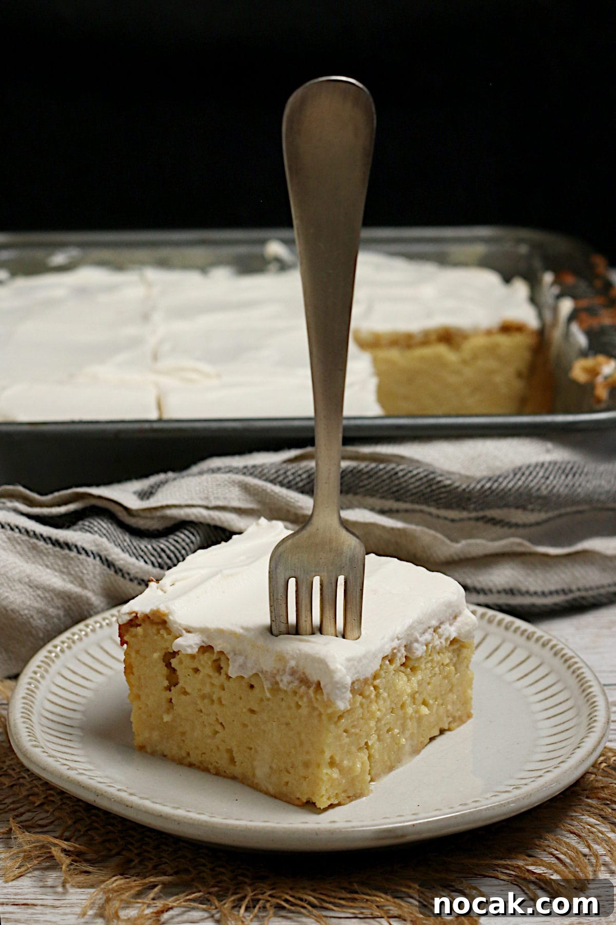 Gluten-Free Corn Tres Leches Cake Recipe for Moist, Flavorful Dessert 3 A slice of gluten-free Corn Tres Leches Cake with a fork stuck into it on a small white plate.