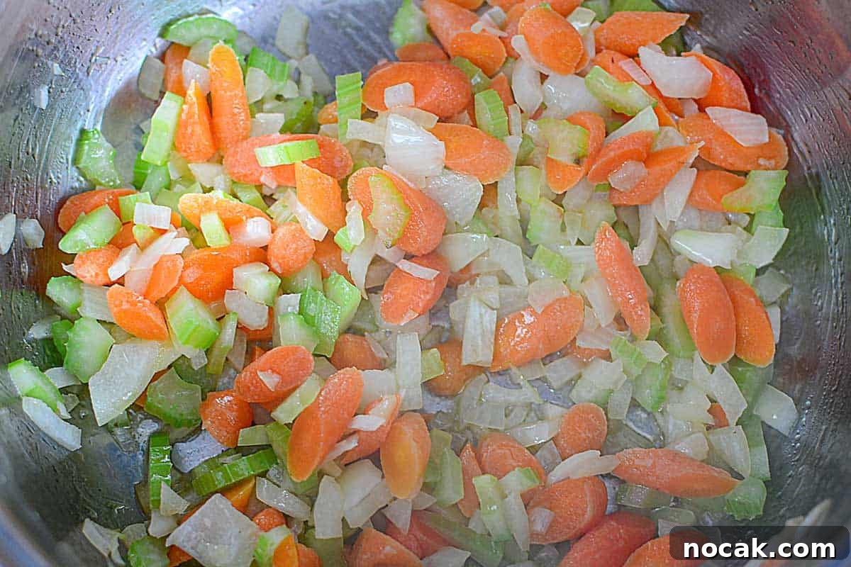 Comforting Chicken and Corn Noodle Soup Recipe 4 chopped celery, onion, and carrots sautéing in pot