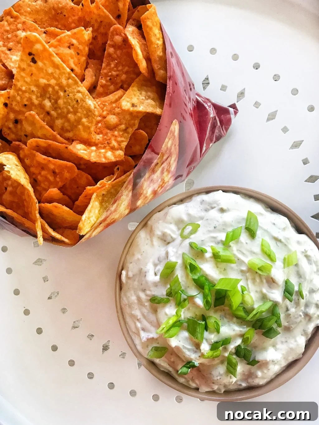 Dorito Dip Recipes: 10 Crowd-Pleasing Dips for Nacho Nights 2 A cut open bag of Doritos next to a container of white dip topped with green onions