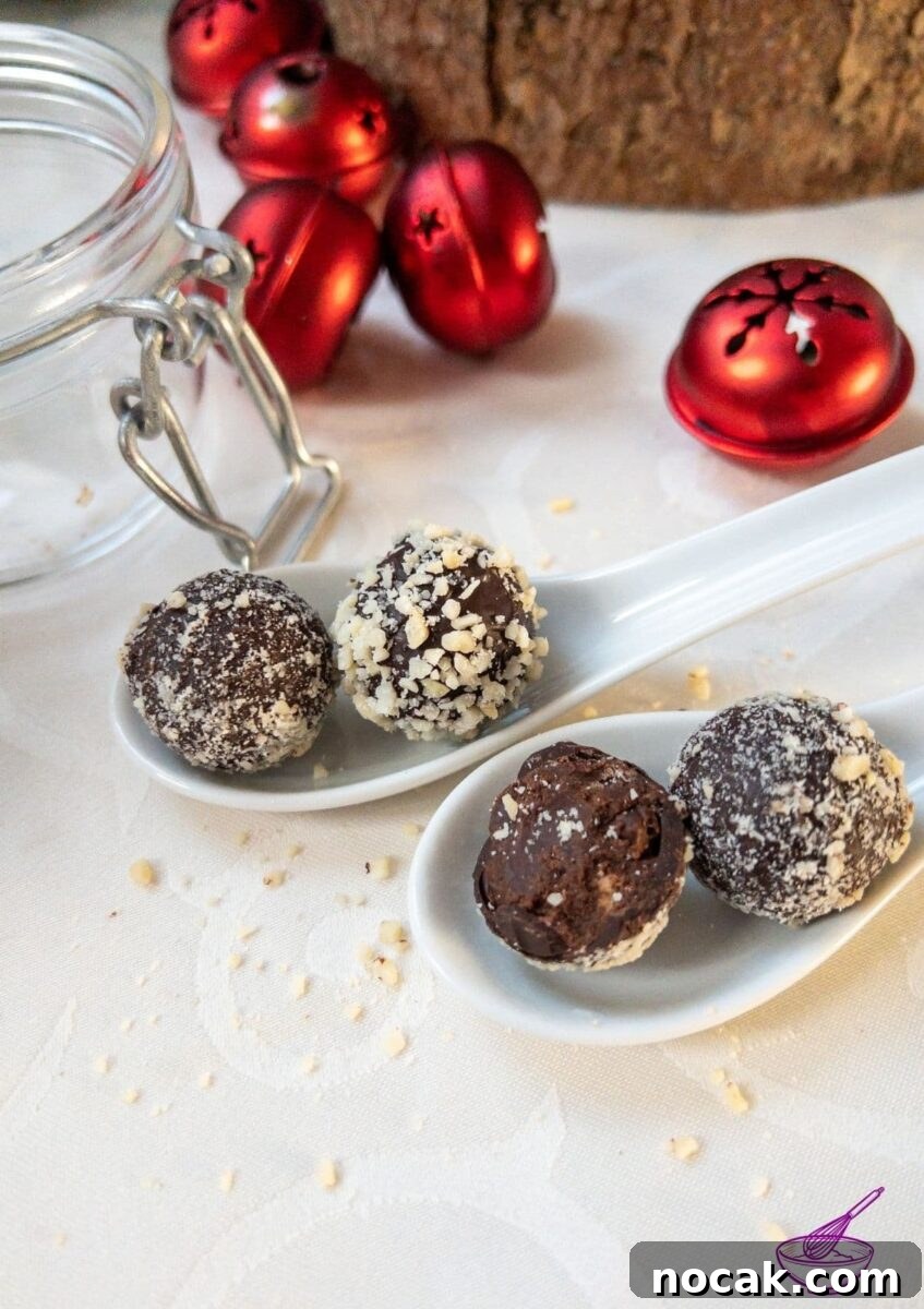 Orange Marmalade Truffles with Dark Chocolate and Liqueur 2 Orange Marmalade Truffles with Dark Chocolate rolled in minced almonds on white tablecloth. Christmas decoration in the back.