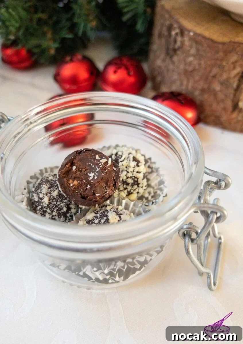 Orange Marmalade Truffles with Dark Chocolate and Liqueur 3 Orange Marmalade Truffles with Dark Chocolate rolled in minced almonds on white tablecloth. Christmas decoration in the back.