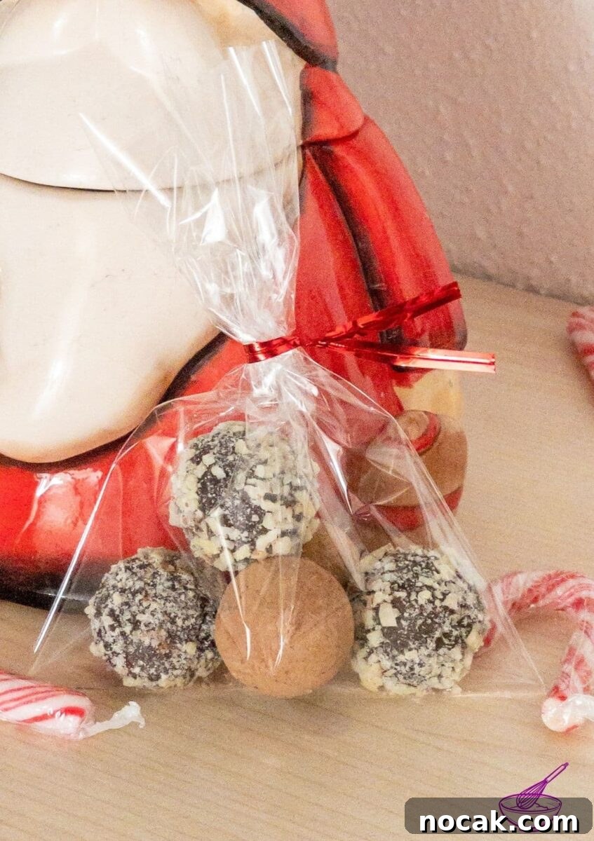 Orange Marmalade Truffles with Dark Chocolate and Liqueur 5 Orange Marmalade Truffles with Dark Chocolate rolled in minced almonds on white tablecloth. Christmas decoration in the back.