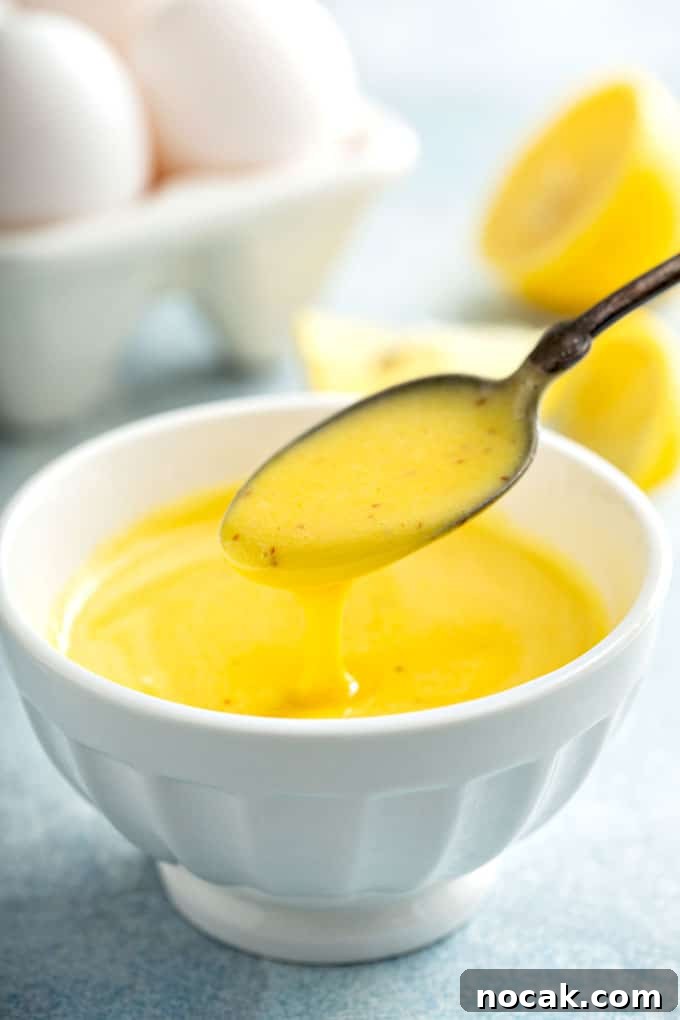 Spoon pouring Hollandaise sauce into a white bowl.