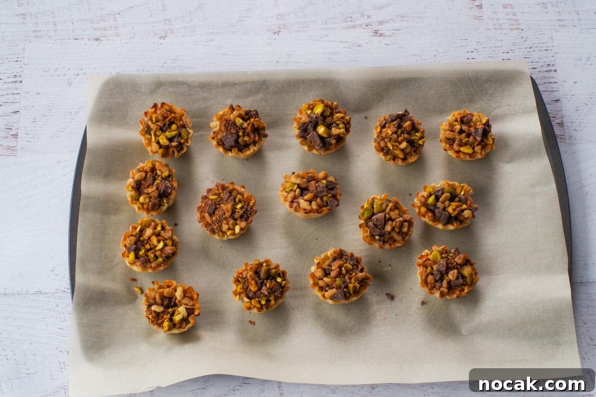 Filled phyllo shells on a parchment covered baking sheet.