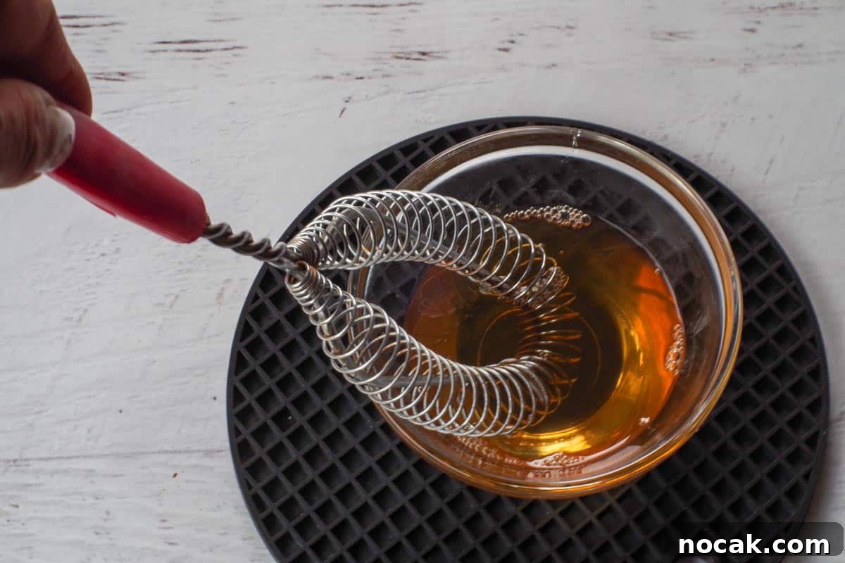 Honey, water and vanilla extract mixed together in small glass bowl with whisk.