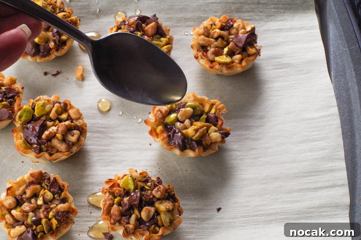 Chocolate Baklava Cups being drizzled with syrup from a small spoon.