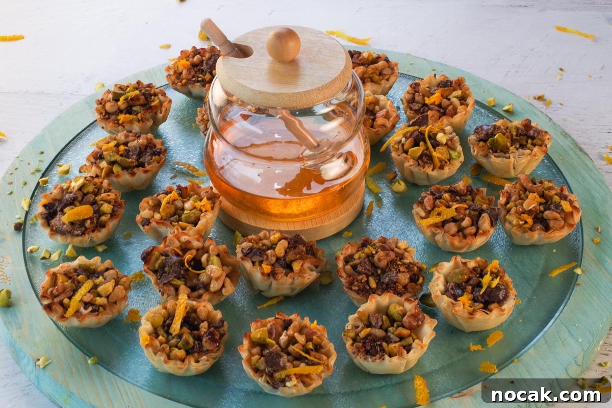 Baklava Cups on a blue glass and wooden powder with a jar of honey in the middle.