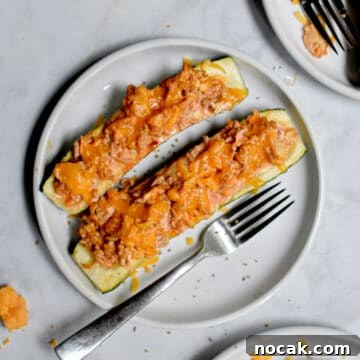 Buffalo Chicken Stuffed Zucchini Boats with Cheesy Filling 10 Two Buffalo Chicken Stuffed Zucchini are on a plate