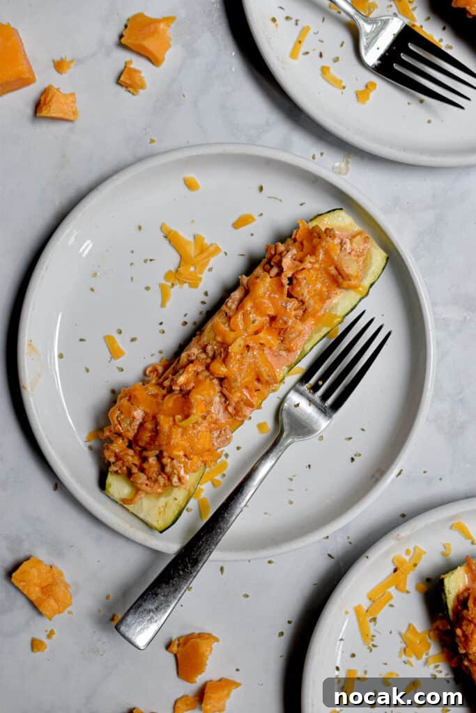 Buffalo Chicken Stuffed Zucchini Boats with Cheesy Filling 9 One half of a zucchini is on a plate with a fork