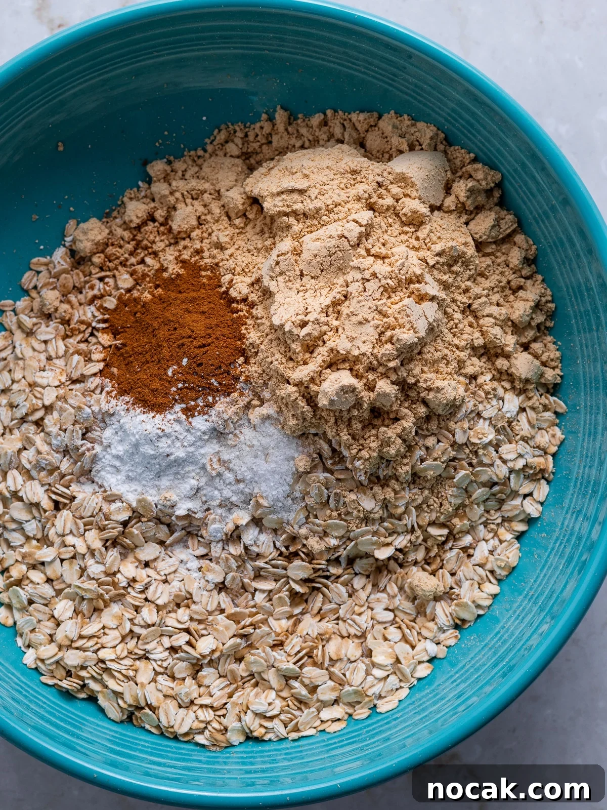 Peanut Butter Baked Oats with Maple and Banana 5 blue bowl with rolled oats, peanut butter powder, cinnamon, salt, baking powder