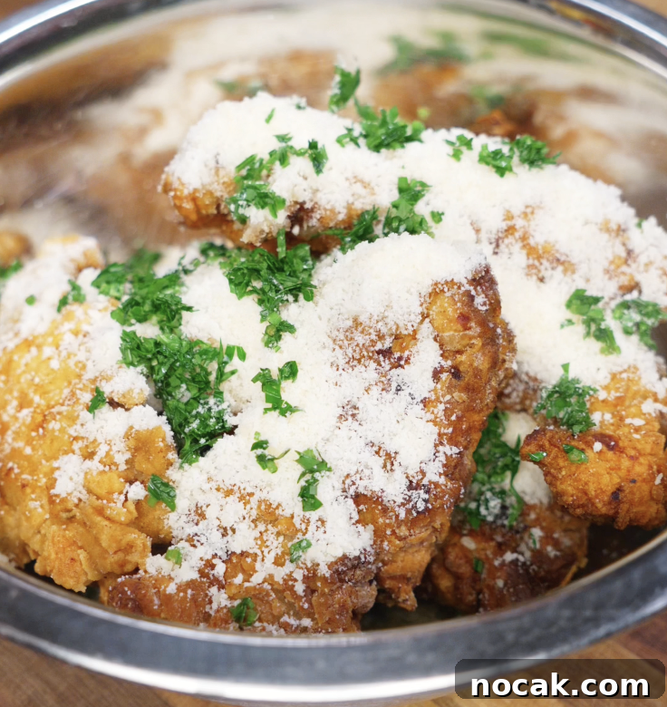 Crispy Garlic Parmesan Chicken Tenders Recipe 8 Freshly fried chicken tenders are placed in a bowl with parmesan and chopped parsley, ready to be tossed in buttery garlic goodness.